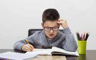 young boy frustrated over homework, writing at home. Boy studying at table. Kid drawing with a pencil
